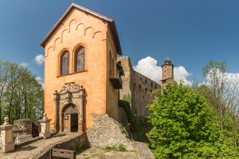 Wejście do średniowiecznego zamku do któego prowadzi kamienny mostek