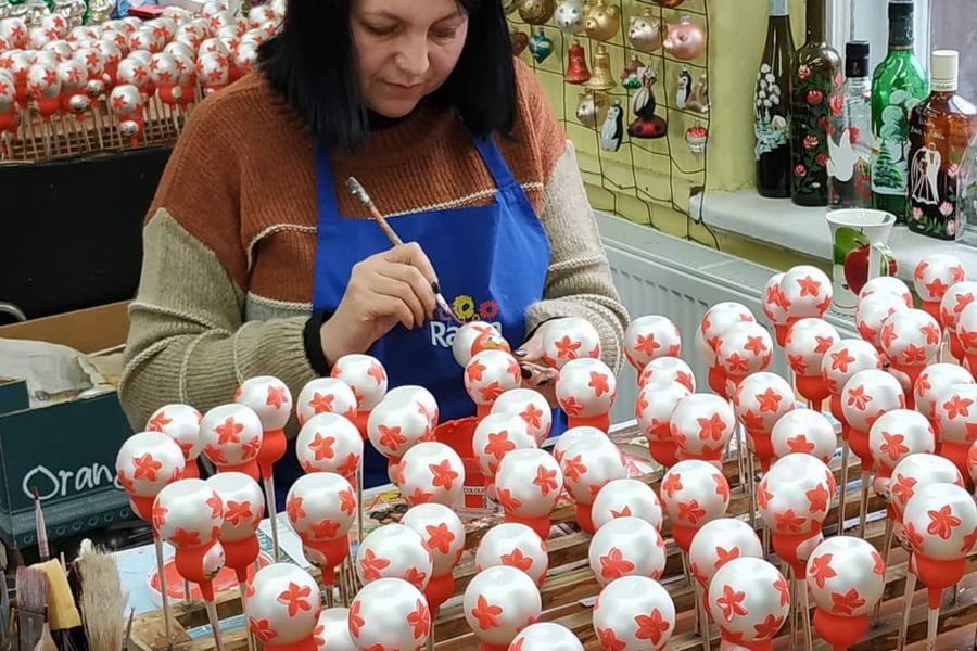 Kobieta dekoruje bombki pomalowane na srebrno