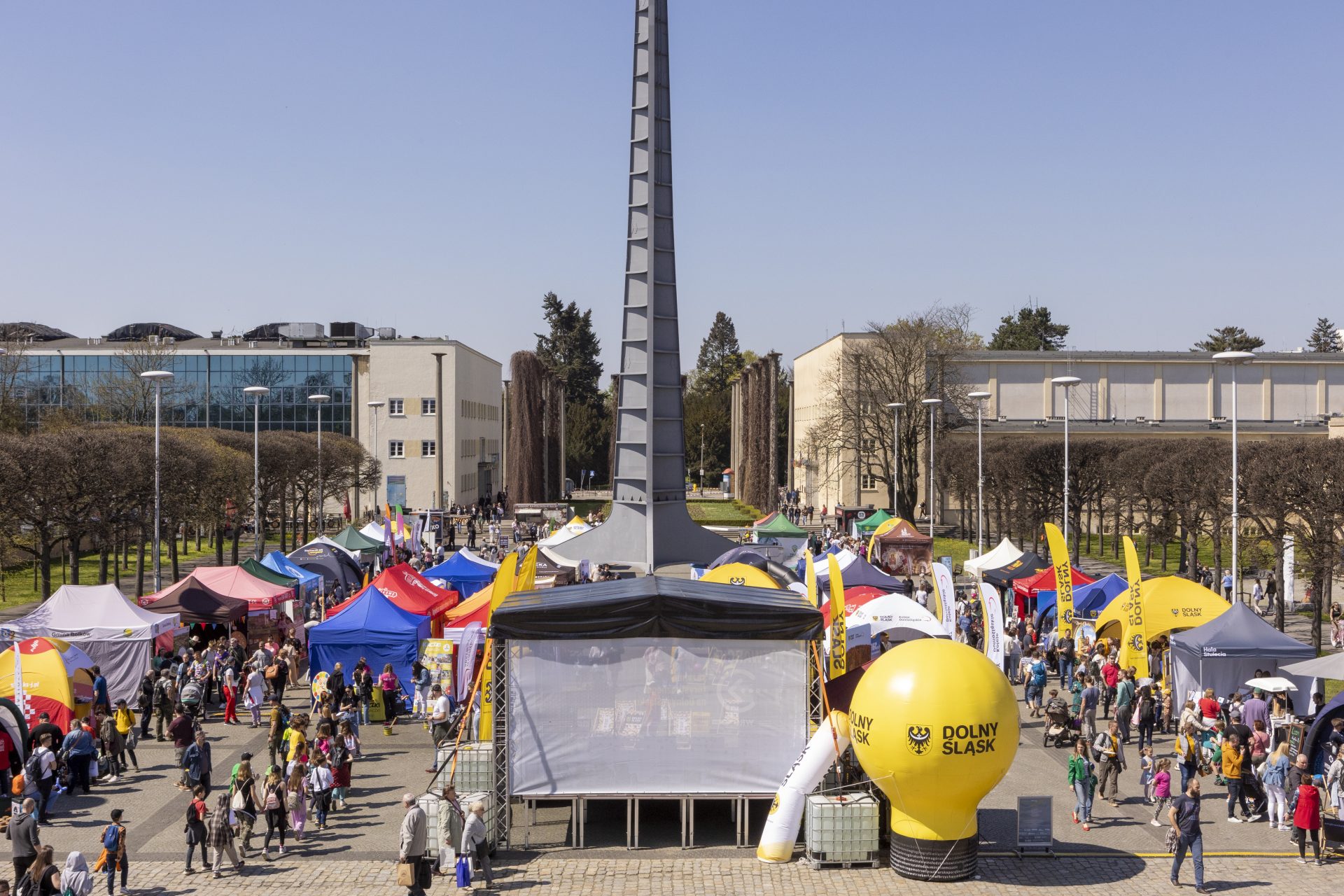 Zdjęcie przedstawia wiele kolorowych stoisk-namiotów podczas imprezy przy Iglicy we Wrocławiu